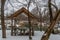 Wooden gazebo, with benches and tables made of wood, on the river bank.