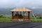 Wooden gazebo mounted on concrete foundation with roof still under construction overlooking small town and mountains in distance