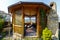 A wooden gazebo with a stone barbecue stove in the backyard of the cottage.  There is a green lawn around the gazebo.