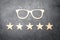 Wooden glasses and five stars on a concrete background. High quality glasses. The best optics. Correction of vision