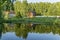 Wooden gottage near old pond and forest with reflection in water