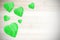 Wooden green hearts on white timbered background.