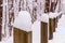 Wooden guardrails covered in snow with woods in the background on a snowy winter day