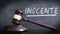 Wooden hammer in a courthouse at verdict of INNOCENT in Spanish `Inocente` in a judgement. Hand written concept with chalk