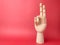 Wooden hand is pointing to a signal of peace on a red background