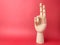 Wooden hand is pointing to a signal of peace on a red background with copy space