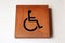 Wooden handicapped mark on the wall in front of the Bathroom disabled.