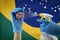 Wooden hands model wearing blue gloves, spraying coronavirus ball with brazilian flag on background