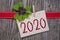 Wooden hang tag with four leaf clover and with happy new year 2020 on wooden weathered background