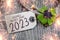 Wooden hang tag and slate with four leaf clover and sparklers with the german words for happy new year - frohes neues jahr 2023 on