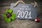 Wooden hang tag and slate with four leaf clover and sparklers with happy new year 2021 on wooden weathered background