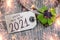 Wooden hang tag and slate with four leaf clover and sparklers with happy new year 2021 on wooden weathered background