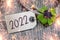 Wooden hang tag and slate with four leaf clover and sparklers with happy new year 2022 on wooden weathered background