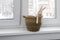 A wooden hare on hinges sits on window near a wicker basket made of jute