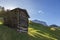 Wooden hayloft construction on green pastures and mountains with blue sky in background