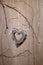 Wooden heart hanging on dry twigs on wood