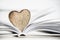 Wooden heart shape on a open book. Love reading concept close up.