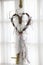 Wooden heart with white ribbon on window