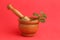 Wooden herb grinder and a green plant inside with a red background