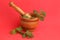 Wooden herb pounder with nettles on red background