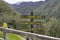 Wooden hiking signposts in Cocora Valley, forested mountains in background, Colombia