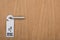 Wooden hotel room door with do no disturb sign on handle