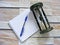 Wooden hourglass, book agenda and pen on the wooden wall background