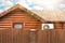 Wooden house with air-conditioning, fenced. Blue sky with clouds. Sunlight