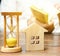 Wooden house and clock. Businessman counting money. Payment of deposit or advance payment for renting a home or apartment. Long-