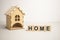 Wooden house and cube blocks spelling HOME on wood board. Concept for financial home loan or money saving for house buying