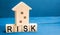 Wooden house and cubes with the word risk. The concept of risk, loss of real estate. Property insurance. Loans secured by home, ap