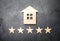 Wooden house and five stars on a gray background. Rating of houses and private property. Buying and selling, renting apartments