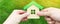 Wooden house in the hand of a young family. Buying a home in a mortgage loan. Real estate concept. Eco friendly home. Government