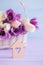 Wooden house with hole in form of heart with beautiful bouquet of tender purple and white tulips on lilac wooden background