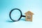 Wooden house and magnifying glass on a blue background. Buying and selling real estate, building new buildings, offices and homes