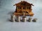 Wooden house miniature, with coin and small key, isolated on gray background. Front view. Space for text.