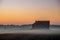 Wooden house in a misty field