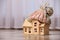 Wooden house model in hat on floor indoors. Heating efficiency