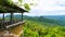 A wooden house on the mountain that overlooks the mountains lined up behind under the sky and clouds