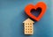 Wooden house and red heart on a blue background. Concept of sweet home. Property insurance. A new home for family. Family comfort