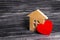 Wooden house with a red heart on a dark wooden background. A house for lovers, a honeymoon. Purchase your own affordable housing
