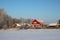 Wooden house with red roof in the forest rural landscape in winter in the Siberian snowdrifts