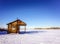 Wooden house rescuers on the shore of a frozen lake covered with snow. Sunny win