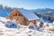 Wooden house in snowy mountains on sunny clear day. European village in Alps in skiing season. Winter nature landscape of snowy