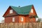 Wooden house under green metal roof with white plastic windows with jalousie