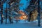 Wooden house with warm light in dark cold winter forest