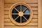 Wooden house window in shape of decorative round ship window made of narrow wooden boards on new wooden house