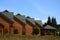 Wooden houses and a gazebo in a hotel on the background of fir trees and blue sky