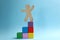 Wooden human figure on top of block staircase against blue background. Career promotion concept