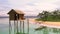 Wooden hut on stilts and a small boat in the sea near the beach of a tropical island with palm trees. 3D illustration